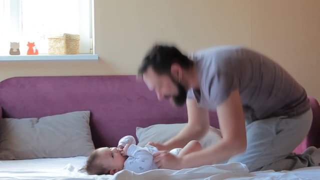 Young father changing diaper and clothes for baby girl At Home