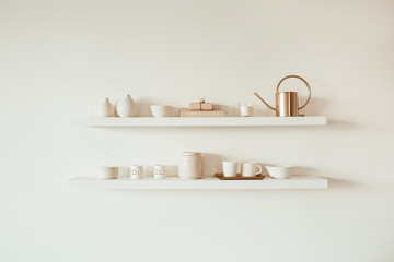Kitchenware utensils on shelf on white background. Ceramic mugs, cups, teapot, tray. Minimal interior design concept.