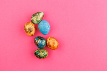 Multi-colored easter eggs lie on a pink background.
