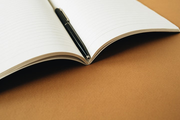Open notebook with pen on ginger orange background. Minimal study, education, business concept.