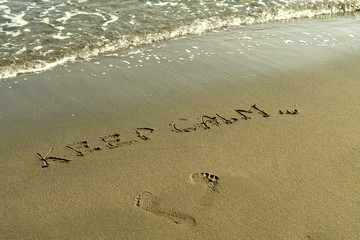 Footprints,  words Keep Calm and wave on beach sand