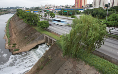 Sewer entering the Tiete River. Sunrise, beginning of the day in metropolis, bright lights and...