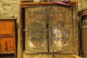 Ancient faded carvings of Tibetan deities and iconography on a wooden box inside an old Buddhist monastery in the village of Marpha.