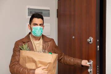 Fototapeta na wymiar A man in a protective medical mask returned home from a grocery store.
