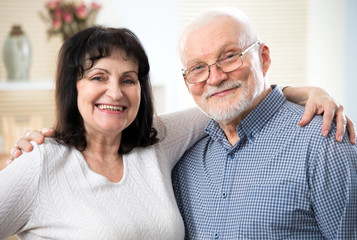 Portrait of a happy elderly couple cuddling and looking at camera