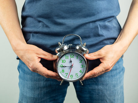 Mann &uuml;ber 40 mit einem Wecker vor seinem Unterleib, Countdown, Alarm