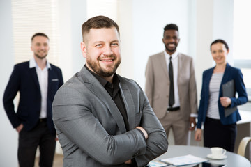 Portrait of happy businessman in an office with colleagues on the background