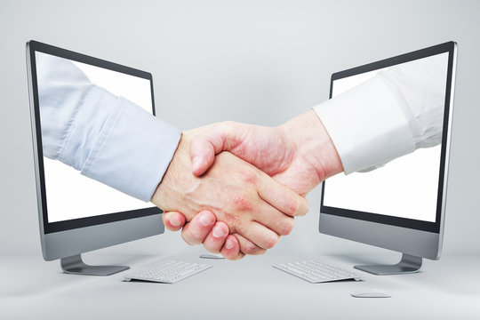 Businessmen Shaking Hands Through Computer Screens