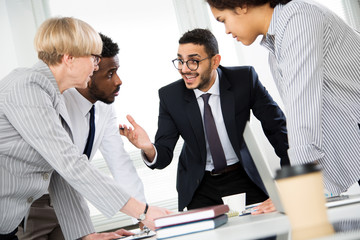International group of young business people working and communicating standing near office desk.