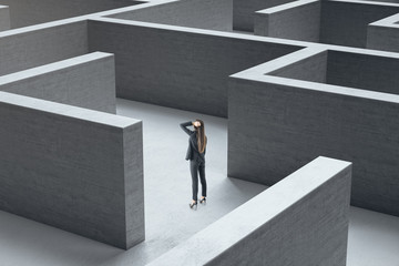 Young businesswoman standing in concrete labyrinth.