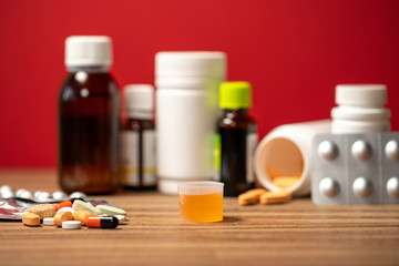 Closeup view photography of orange  syrup medicine in special container cap ad pile of different...