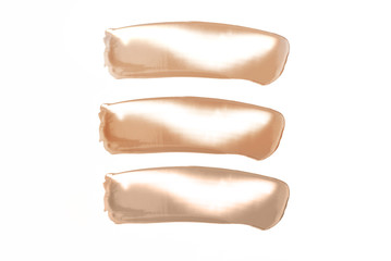 Smears of different tonal creams on an isolated white background.