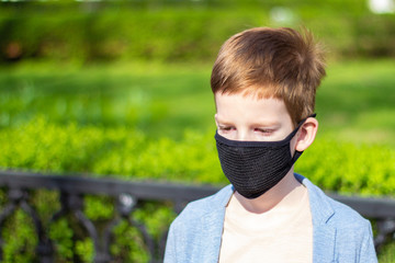 Saddens kid boy wearing black protective mask outdoor. During pandemic covid-19. Antivirus...