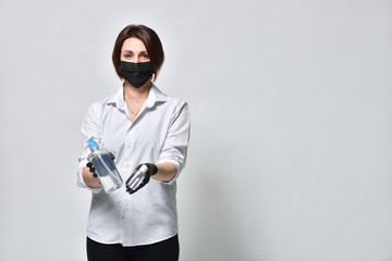 A woman in black gloves demonstrates a protective antiseptic gel on a white background, during the coronavirus pandemic.