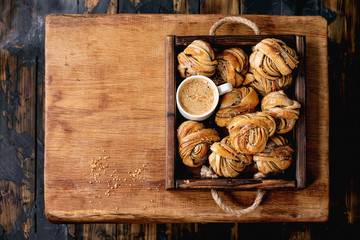Traditional Swedish cardamom or cinnamon sweet buns Kanelbulle in wooden tray, cup of coffee on...