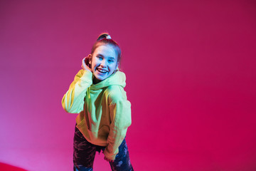 Young stylish girl dancing in the Studio on a colored neon background. Music dj poster design.