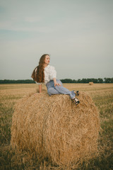Naklejka na ściany i meble Portrait of a girl in a vintage dress on nature background. A girl with long hair in a field on a summer sunny day. Fashion vintage dress.