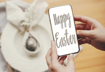 Happy Easter text. Easter greetings lettering. Phone with greeting on screen and stylish Easter...