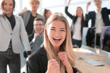 Fototapeta na wymiar young woman on the background of a jubilant business team.