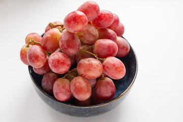fresh large grapes in a ceramic bowl on a white background