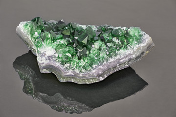 deep color emerald in geode on grey background
