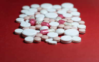 Heap of white pills, tablets, capsules on red background. Drug prescription for treatment medication health care concept wth copy space.