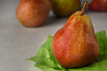 Red ripe pears on a light background. A Pear on a piece of crumpled green wrapping paper and three pears on background. Fruit background. Copy space. Selective focus.