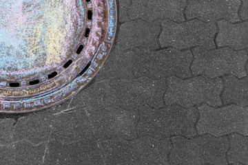 Manhole cover in a Berlin backyard, painted with chalk by children