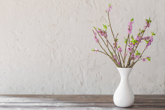 daphne flowers in vase on old wooden table on background white w