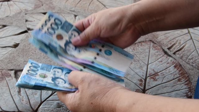 Counting a bulk of 1000 Philippine peso cash on a table by hand