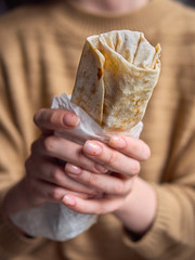 Close Up no face detail shot of woman in yellow sweater holding delicious falafel kebab roll...