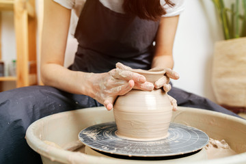 close-up female hands at work behind the potter's wheel
