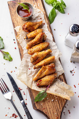 Grilled chicken wings on a wooden board with tomato sauce, Top view