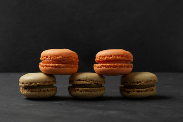 Mixed of Colorful Macarons cake on dark concrete background with copy space. Green and orange french macaroons.