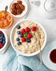Oatmeal porridge with blueberry, raspberries, jam, vertical, top view. Breakfast with berries
