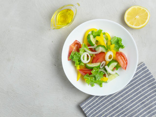 Fresh vegetable salad on a white plate on a grey concrete background. Vegan, vegetarian.