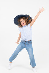 young girl in a hat jumps for joy on a white background