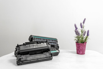 Cartridges group lie on an office white table against a white wall.