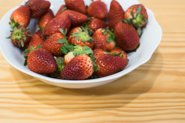 Fresas rojas en un bol blanco sobre mesa de madera