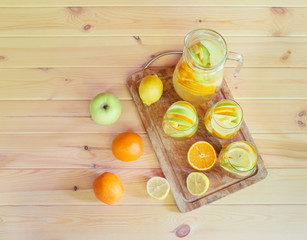 White wine sangria with fruits in glasses and pitcher on cutting board and fresh fruits near. Top...