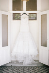 Fototapeta na wymiar A white wedding dress hanged on the hanger. Buying a wedding dress.