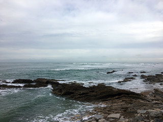 Fototapeta premium Waves crashing on rocks with cloudy weather