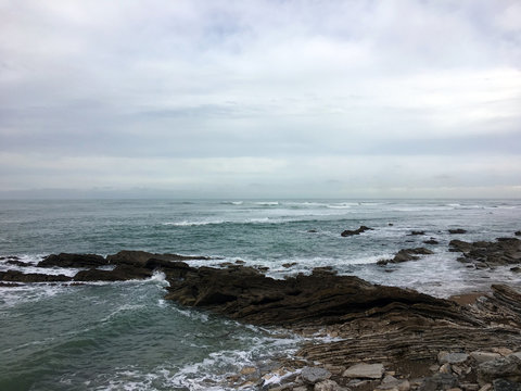 Waves crashing on rocks with cloudy weather