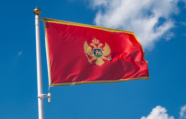 Montenegro flag waving in sunny blue sky.