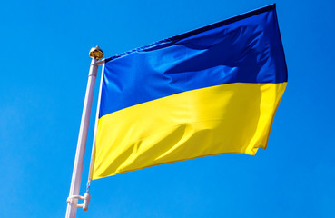 The flag of Ukraine waving against a clear blue sky.