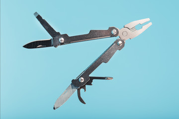 The multitool multi-function tool hovers on a blue background. The concept of an expanded multi-tool with free space.