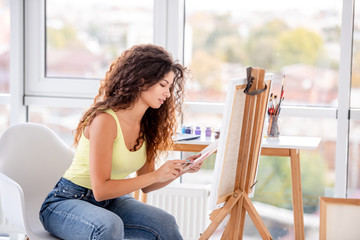 Smiling artist painting on easel