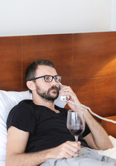 Young businessman talking at the phone in hotel room ordering room service during self-isolation in quarantine