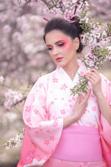 Beuatiful girl wearing japanese traditional kimono in peach orchard during spring - 334171683