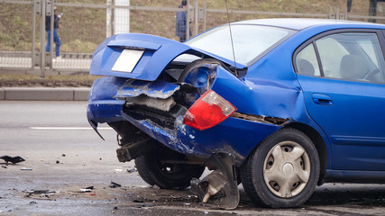 Side view. Back of blue color car damaged and broken by accident on the road. 